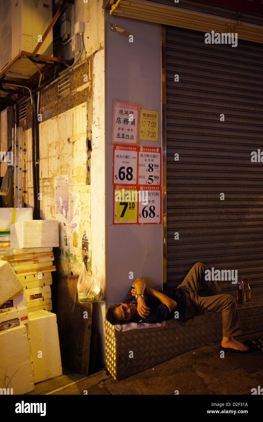 Hong Kong, China, homeless man is sleeping in front of a closed business Stock Photo