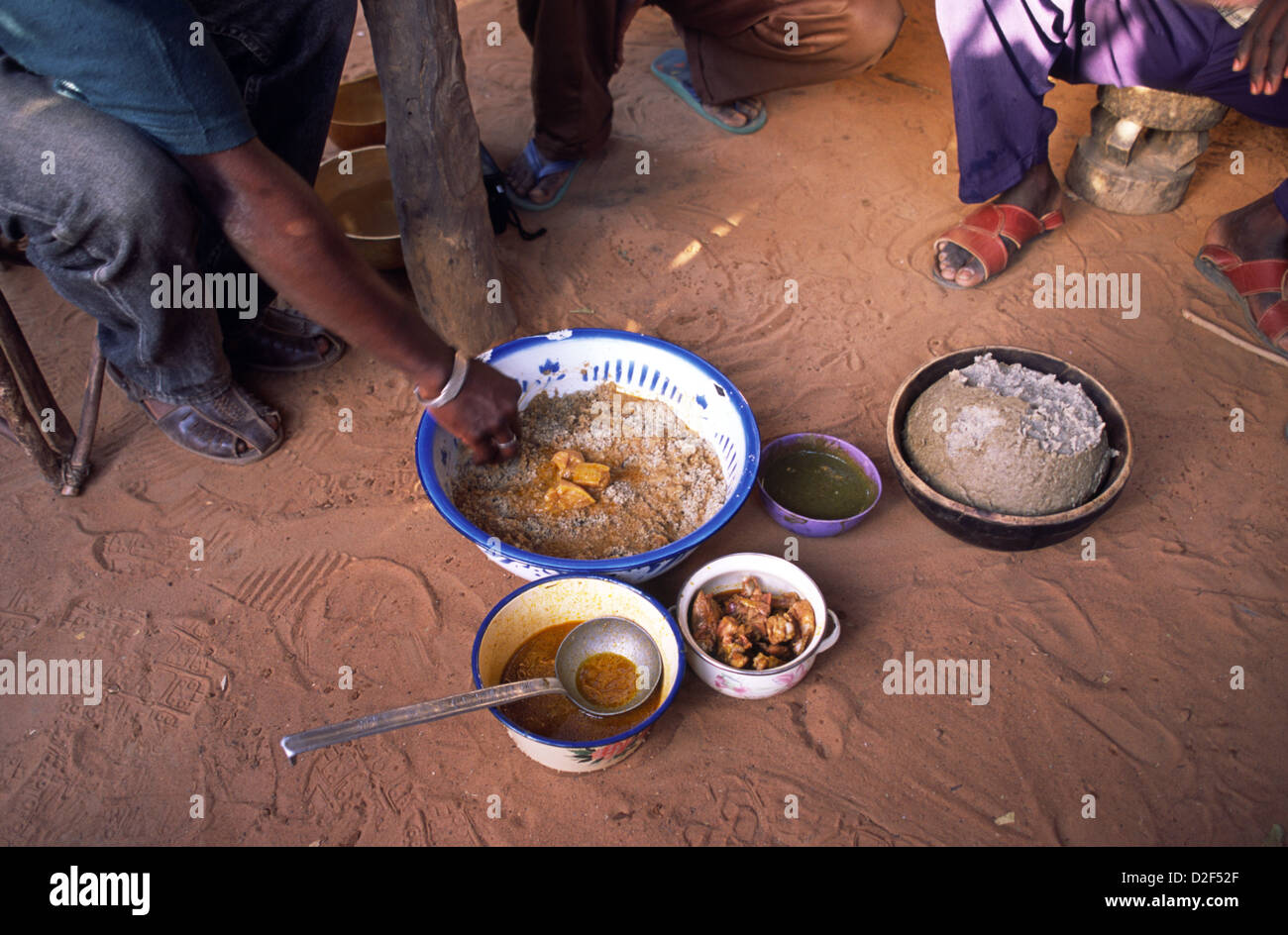 Meals are eaten with fingers in Mali, Africa. Rice, to (millet,) okra sauce or gumbo, goat meat and tomato and onion sauce. Stock Photo