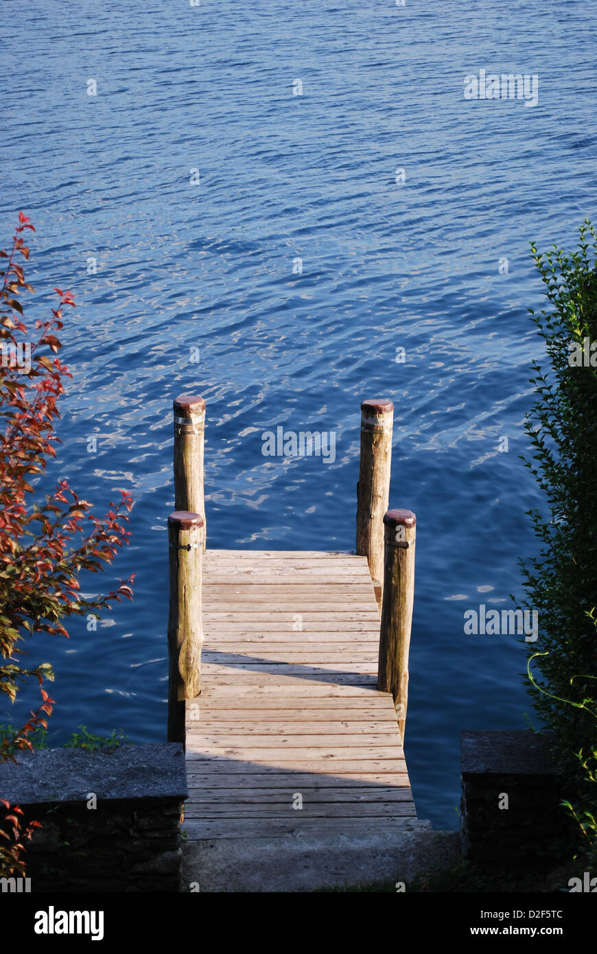 Small wooden dock on blue water, Orta lake, Italy Stock Photo