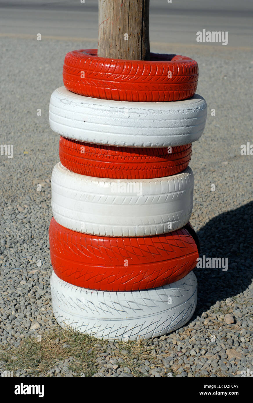 red and white painted car tyres protecting a telephone pole at a petrol station in morocco Stock Photo