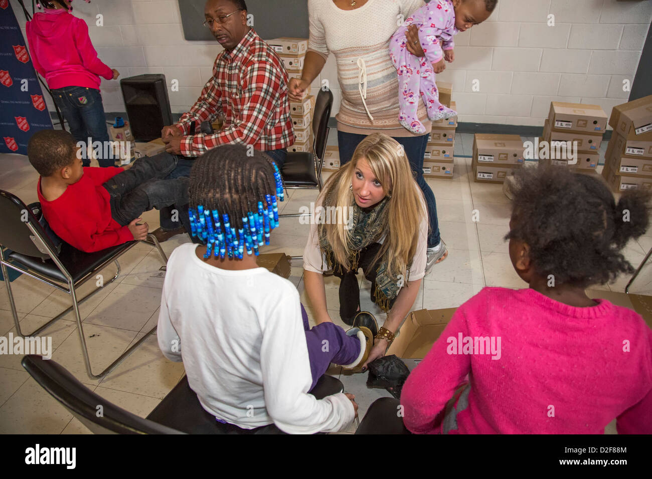 Residents of a Salvation Army shelter for homeless women and children try on winter boots donated by Toyota. Stock Photo