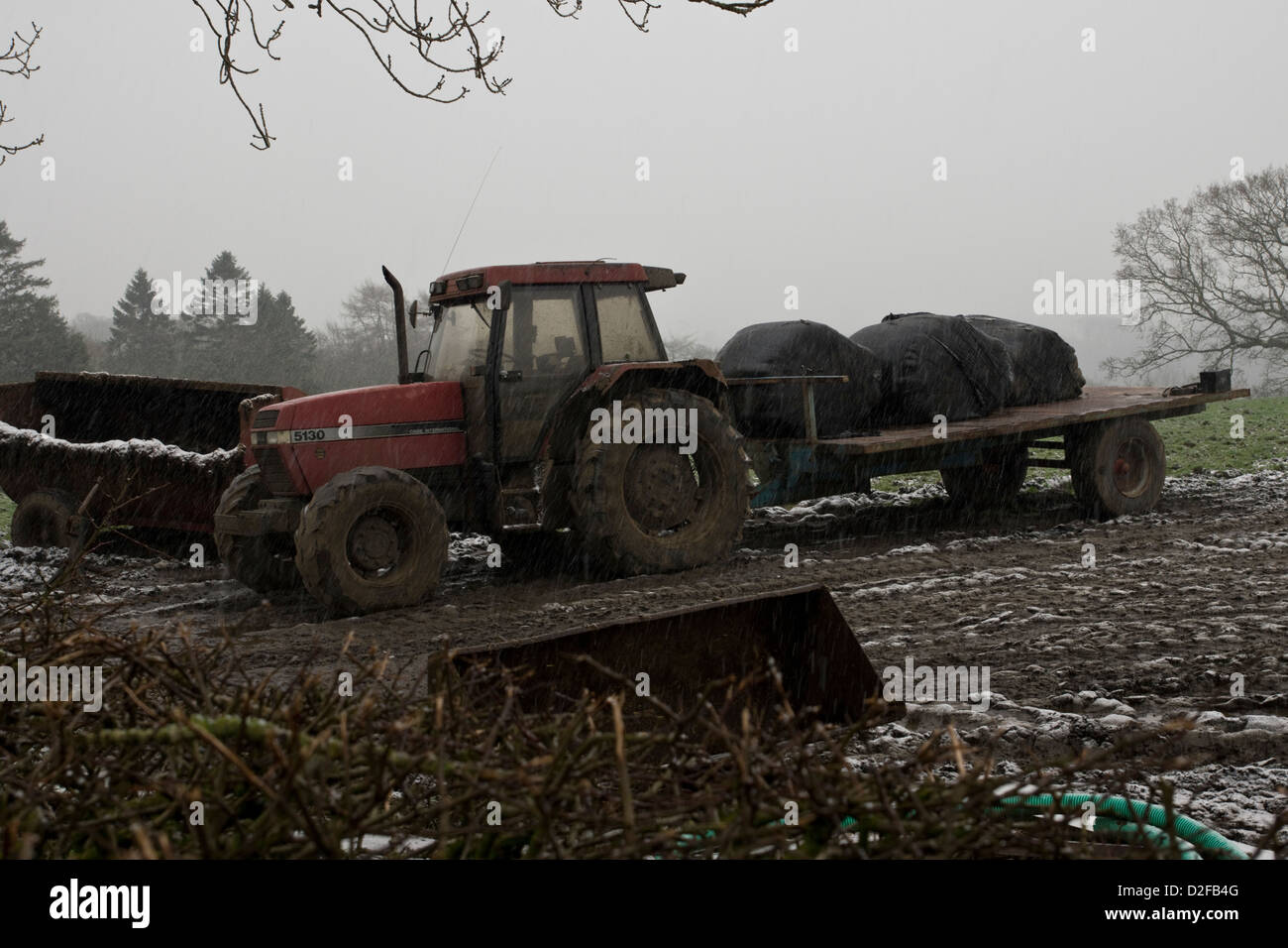An agricultural tractor parked up in the farmers field in the snow. Stock Photo