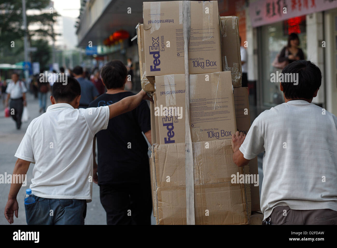 Shenzhen, China, three men push packages labeled FEDEX Stock Photo