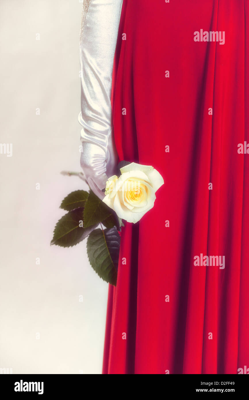 a woman in a red dress is holding a white rose in her hand Stock Photo ...