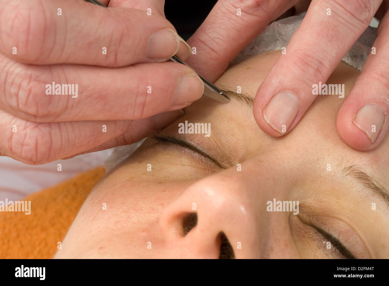 Woman's eyebrow is being depilated in a beauty salon Stock Photo