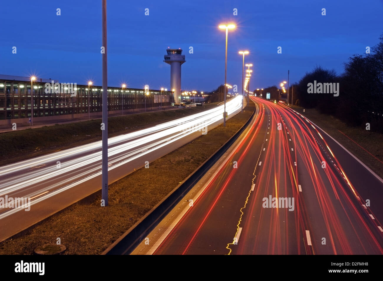 traffic lights at night on highway with airport tower of the liege airport Stock Photo