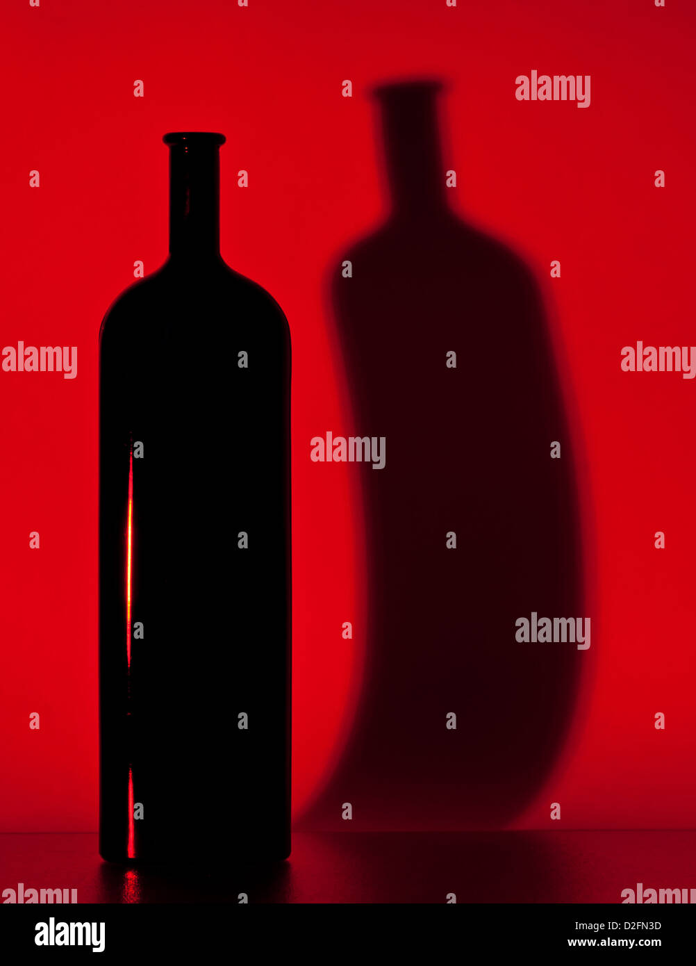 black bottle and its shadow on a red background Stock Photo