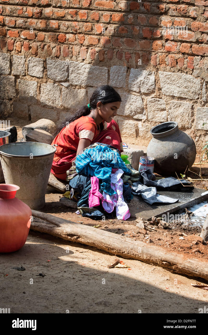 Indian teenage girl washing clothes by hand outside her village home. Andhra Pradesh, India Stock Photo