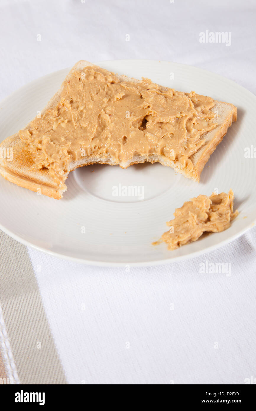Peanut butter on slice of bitten bread Stock Photo