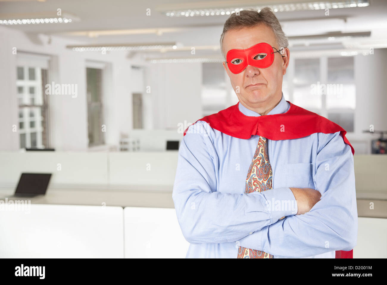 Portrait of serious businessman in superhero costume in office Stock Photo