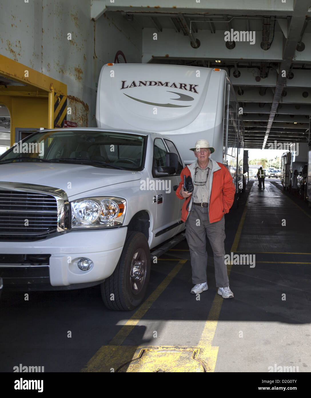 View through vehicle deck on the Port Angeles to Sidney ferry, with man standing beside a fifth-wheel RV and white dodge truck. Stock Photo