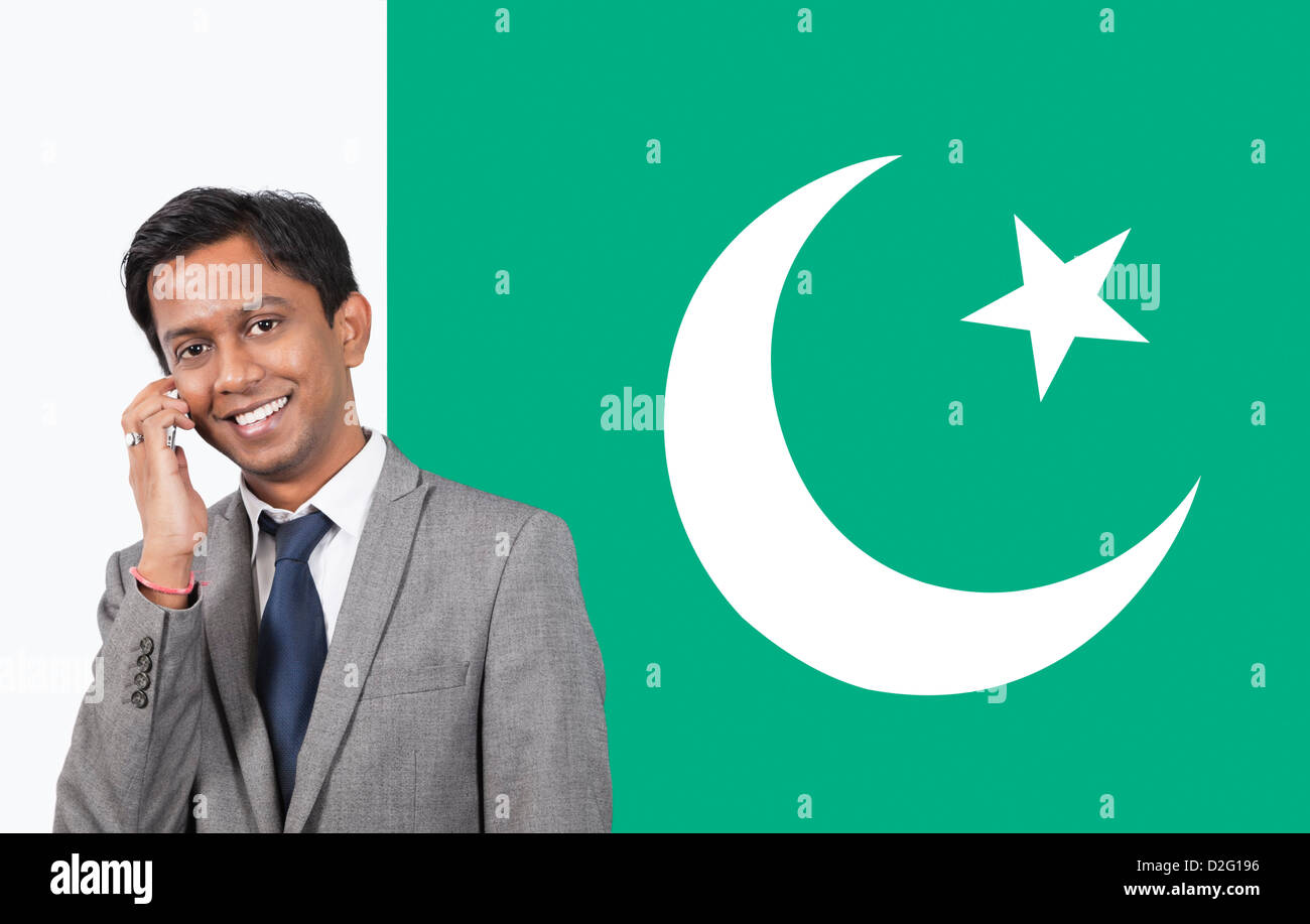 Portrait of young businessman using cell phone over Pakistani flag Stock Photo