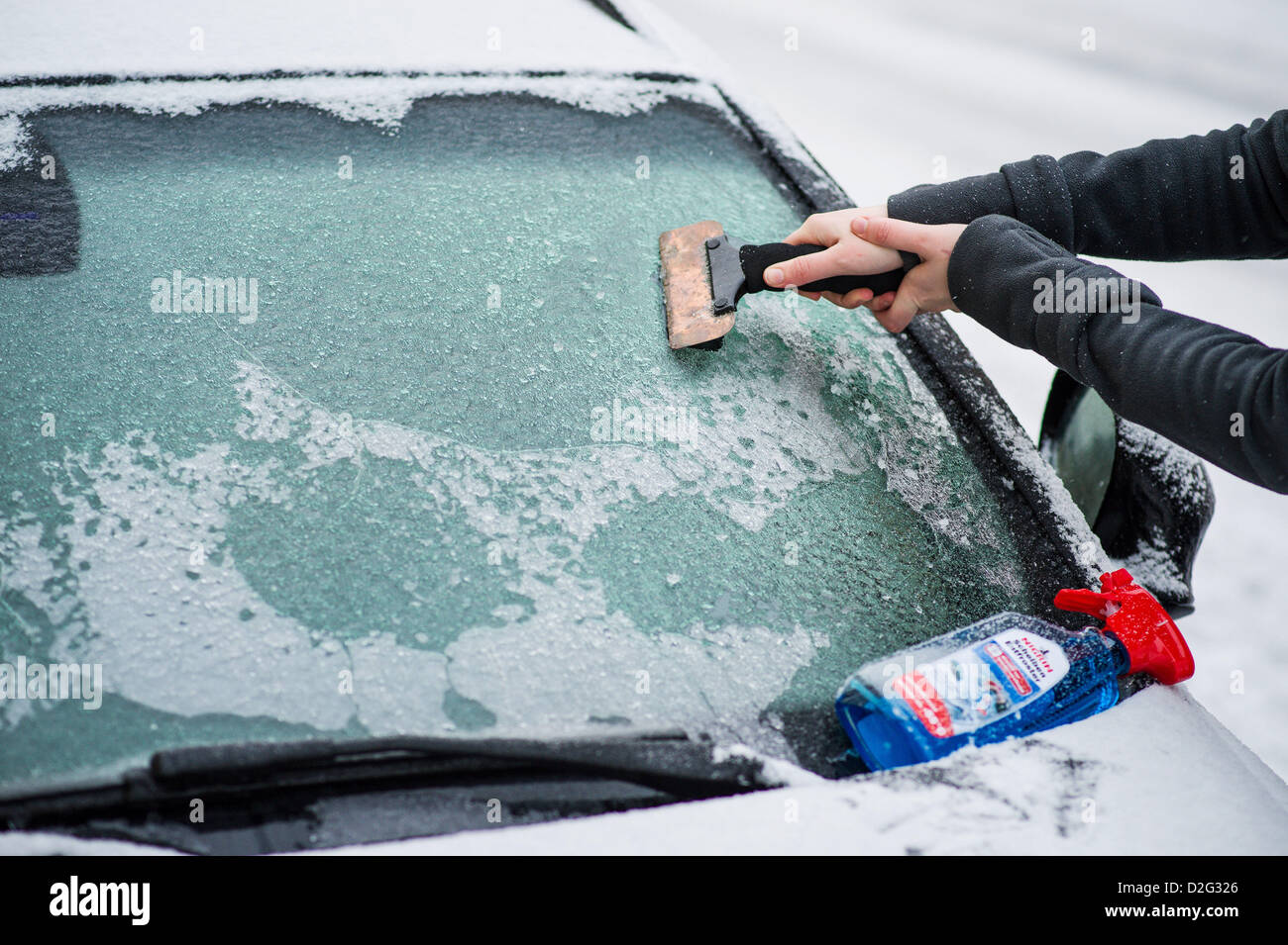 A woman scrapes ice off her car with an ice scraper in Bamber, Germany