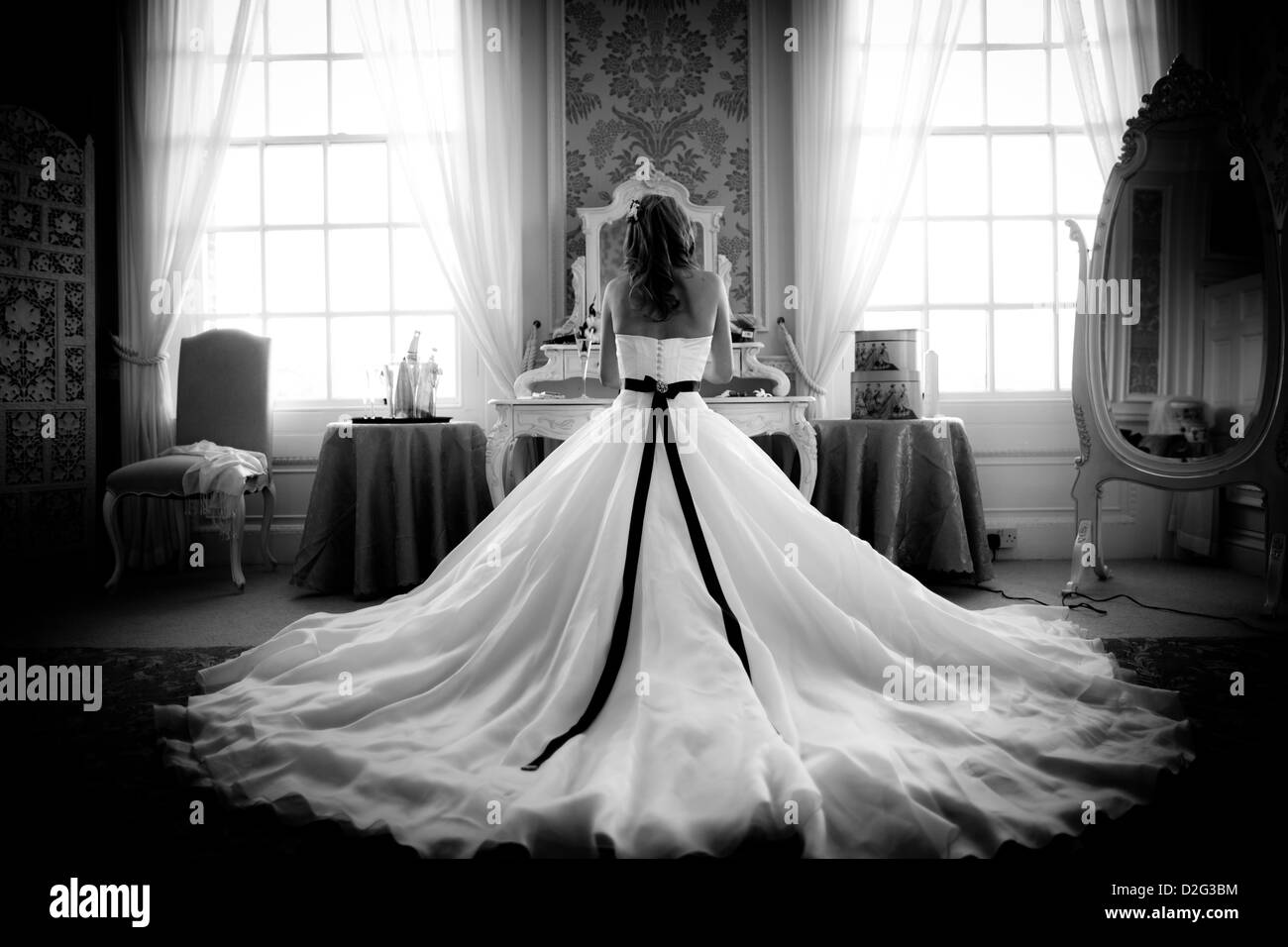 Black and white photo of a bride sitting in her beautiful wedding dress with her back to the camera Stock Photo