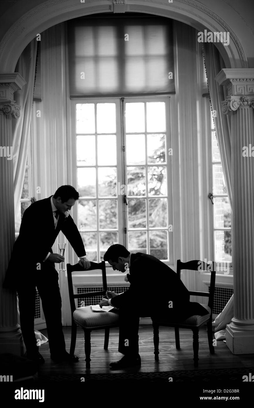 Black and white vertical photo of a Groom and his Best Man reading over their speeches for the wedding reception Stock Photo