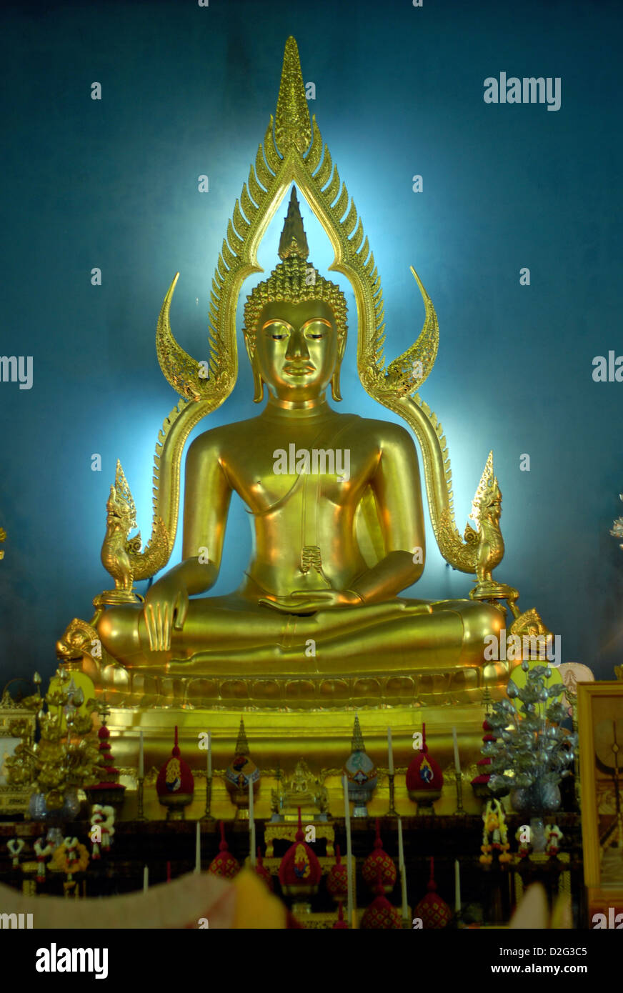 golden statue of a seated thai buddha at a shrine in a temple in ...