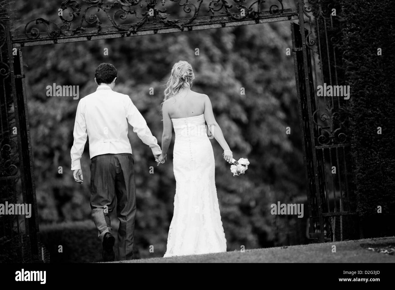 Black and white landscape photo of a Bride and Groom walking away from the camera outside Stock Photo