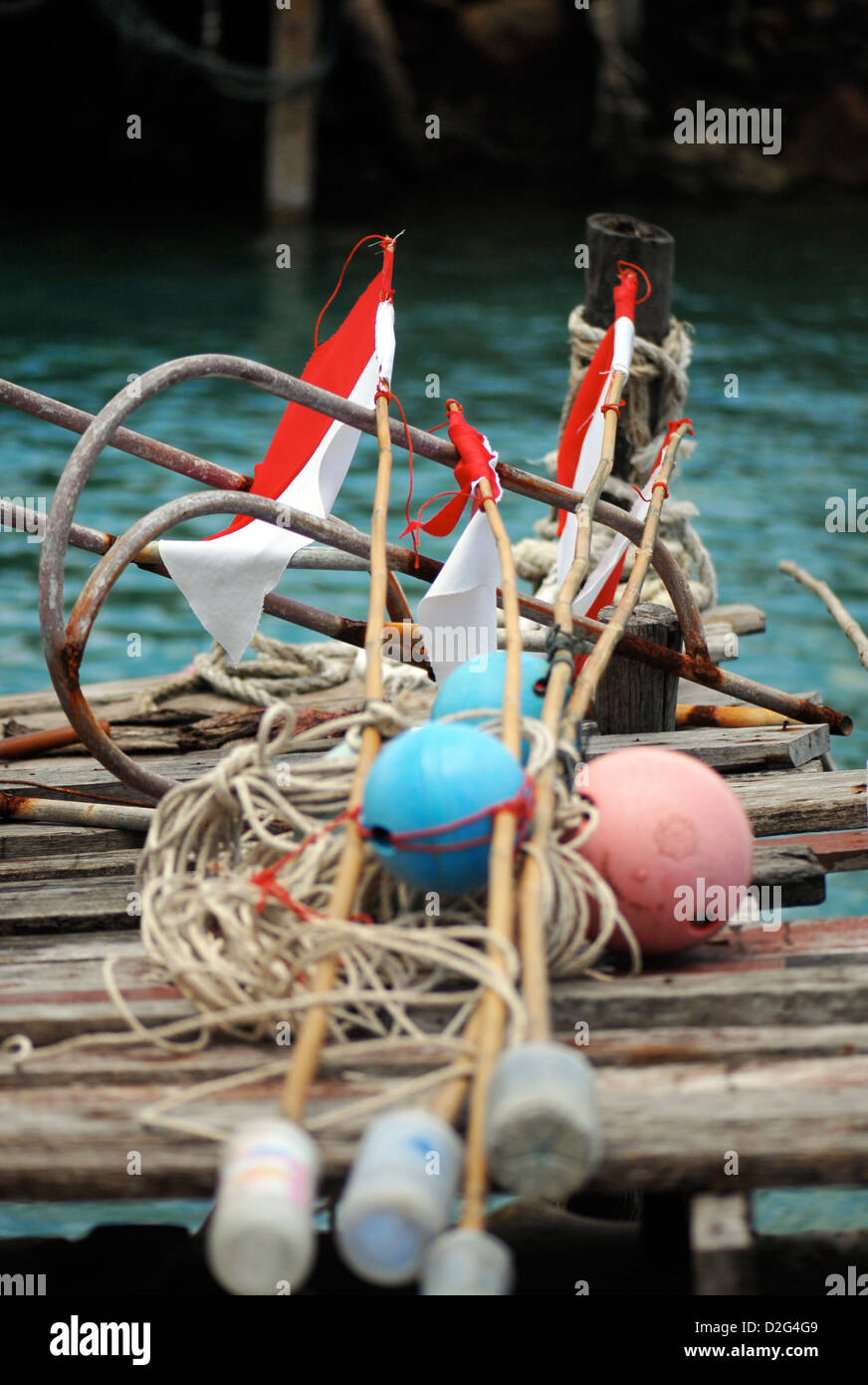 fishing floats and net markers lie in the sun on a rickety old wooden jetty Stock Photo