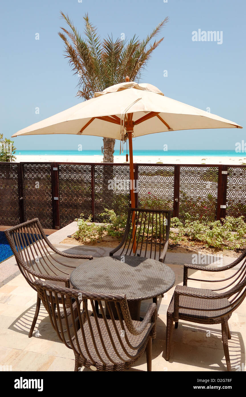 Chairs and umbrella near swimming pool by a beach of the luxury hotel, Saadiyat island, Abu Dhabi, UAE Stock Photo