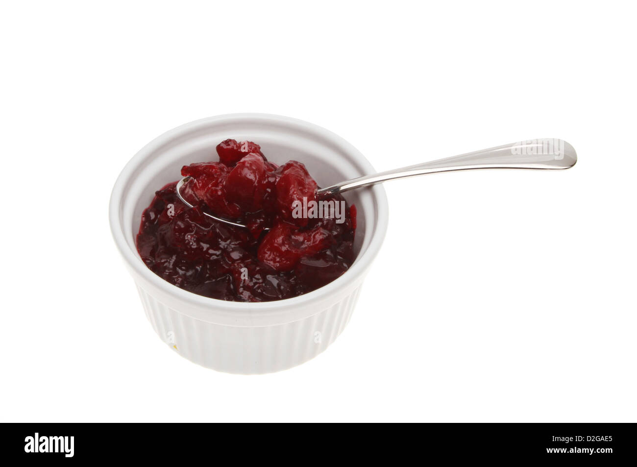 Cherry preserve with whole fruit and a spoon in a ramekin isolated against white Stock Photo