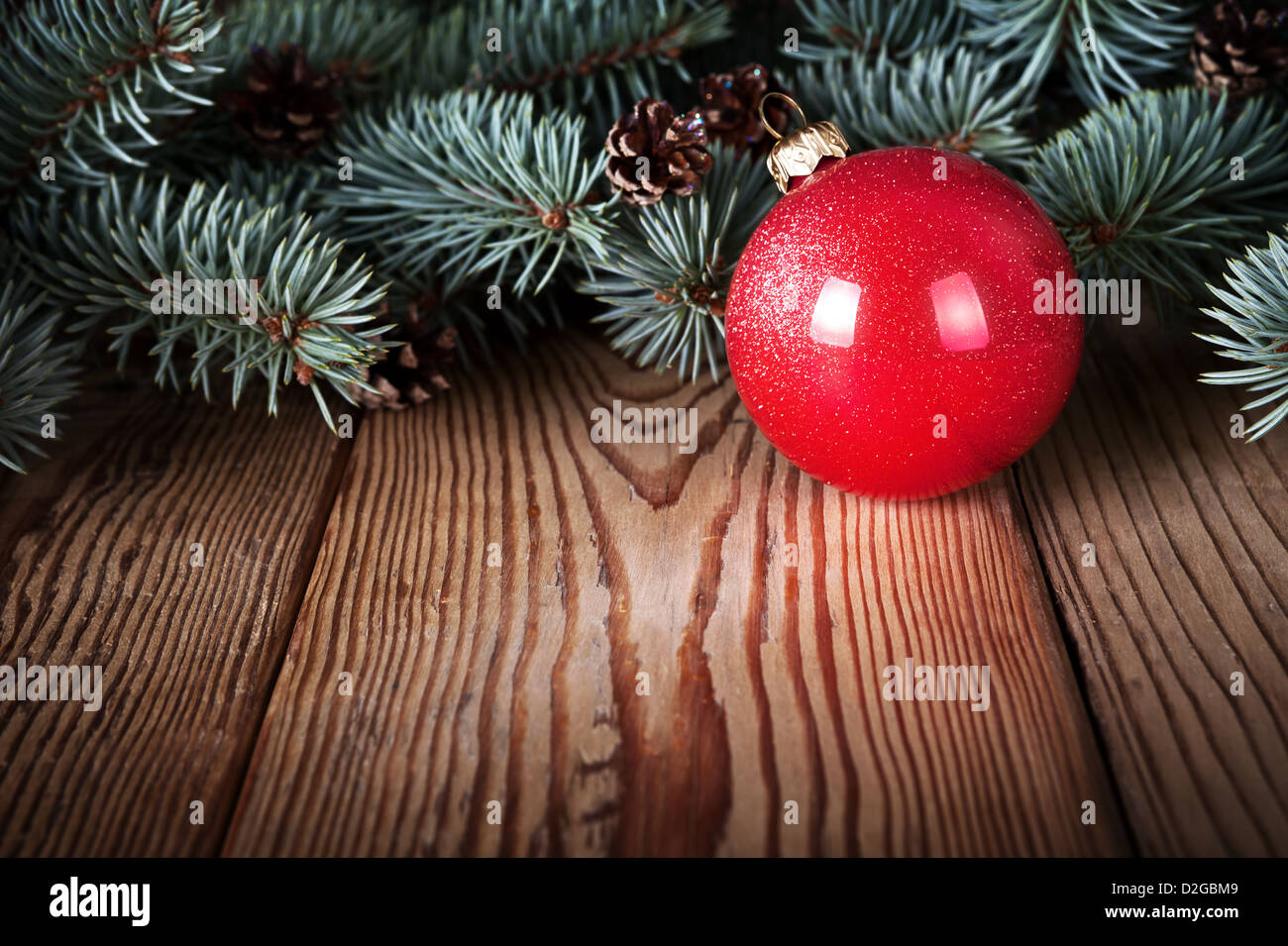 Red christmas ball on wooden background with branches of silver spruce. Copy space Stock Photo