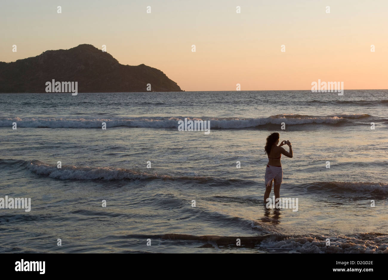 Young woman taking digital photos at sunset, Mazatlan, Sinaloa State, Mexico. Stock Photo