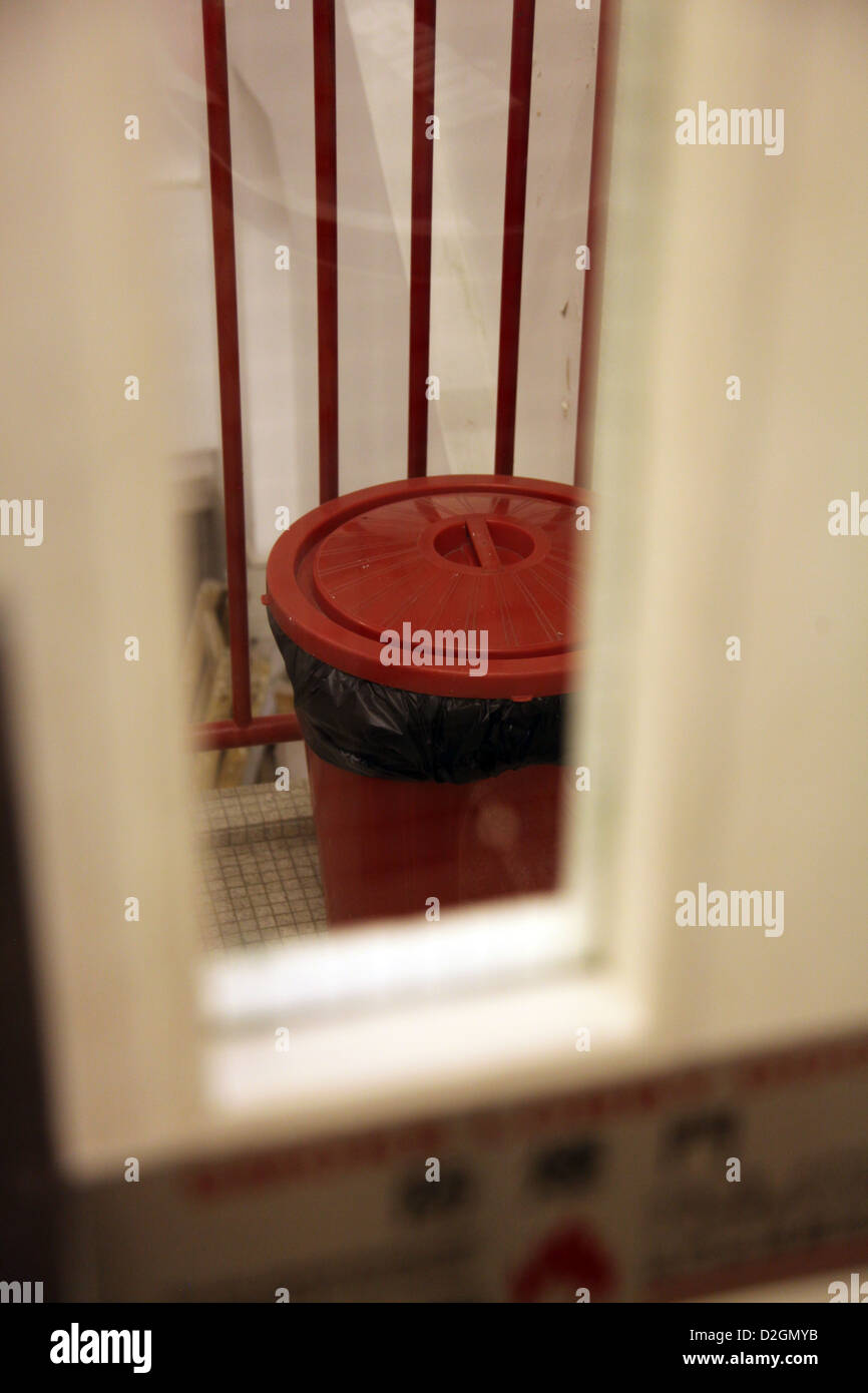 It's a photo of a of a bin or trash can or rubbish bin that we can see through the window of a door in a corridor Stock Photo