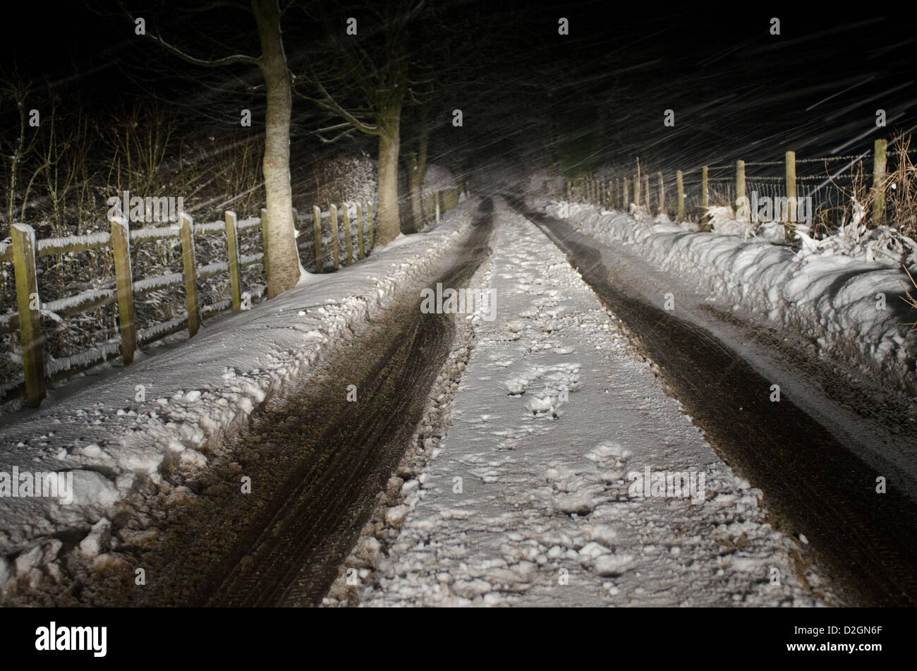 Narrow country road in snow at night Stock Photo