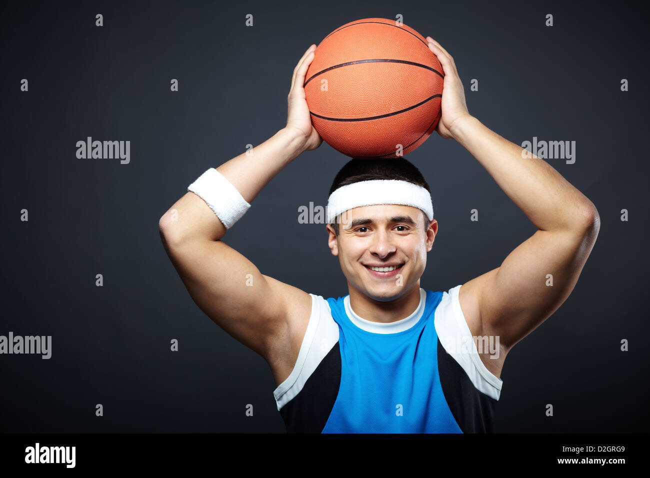 Portrait of handsome guy in sportswear with basket ball on his head looking at camera Stock Photo