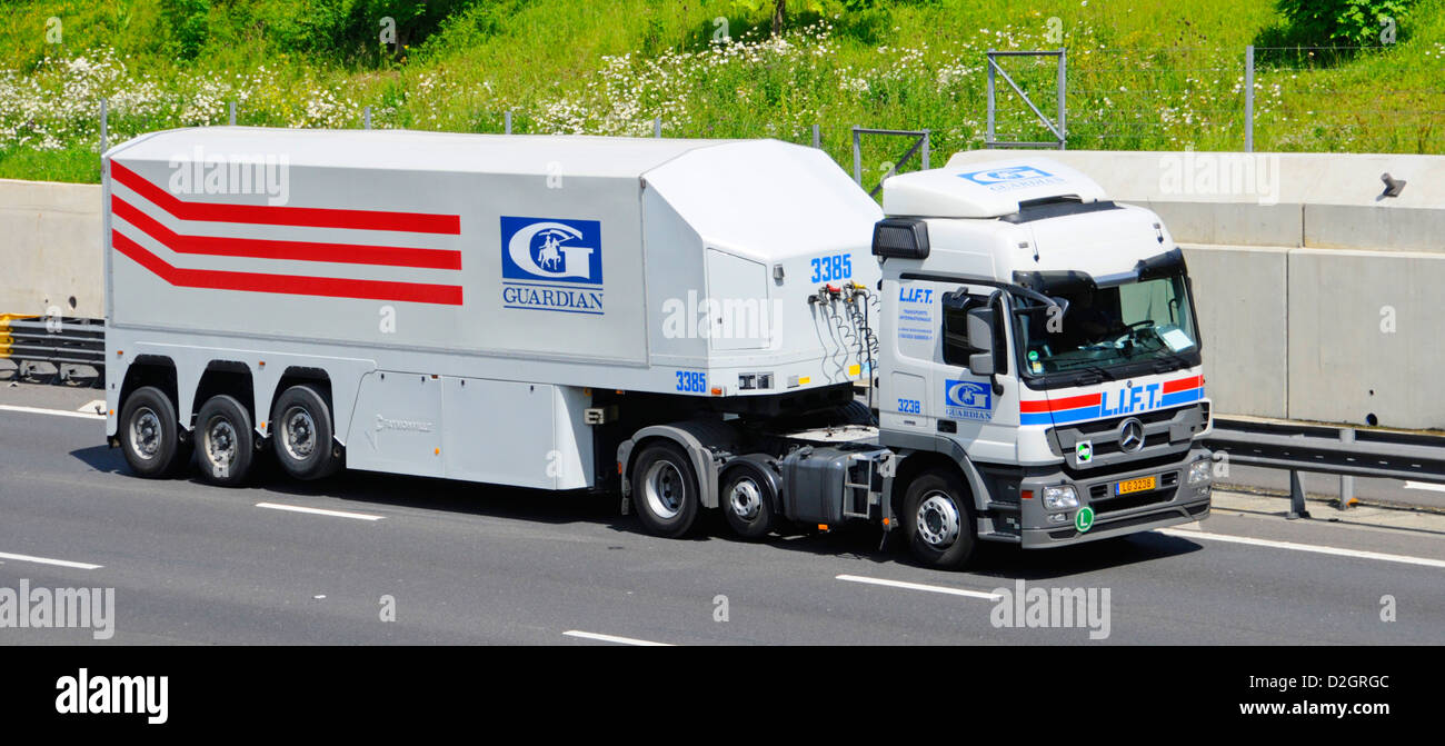 Guardian Industries articulated trailer with raised axle and Mercedes Benz hgv delivery lorry truck driving along M25 motorway Essex England UK Stock Photo