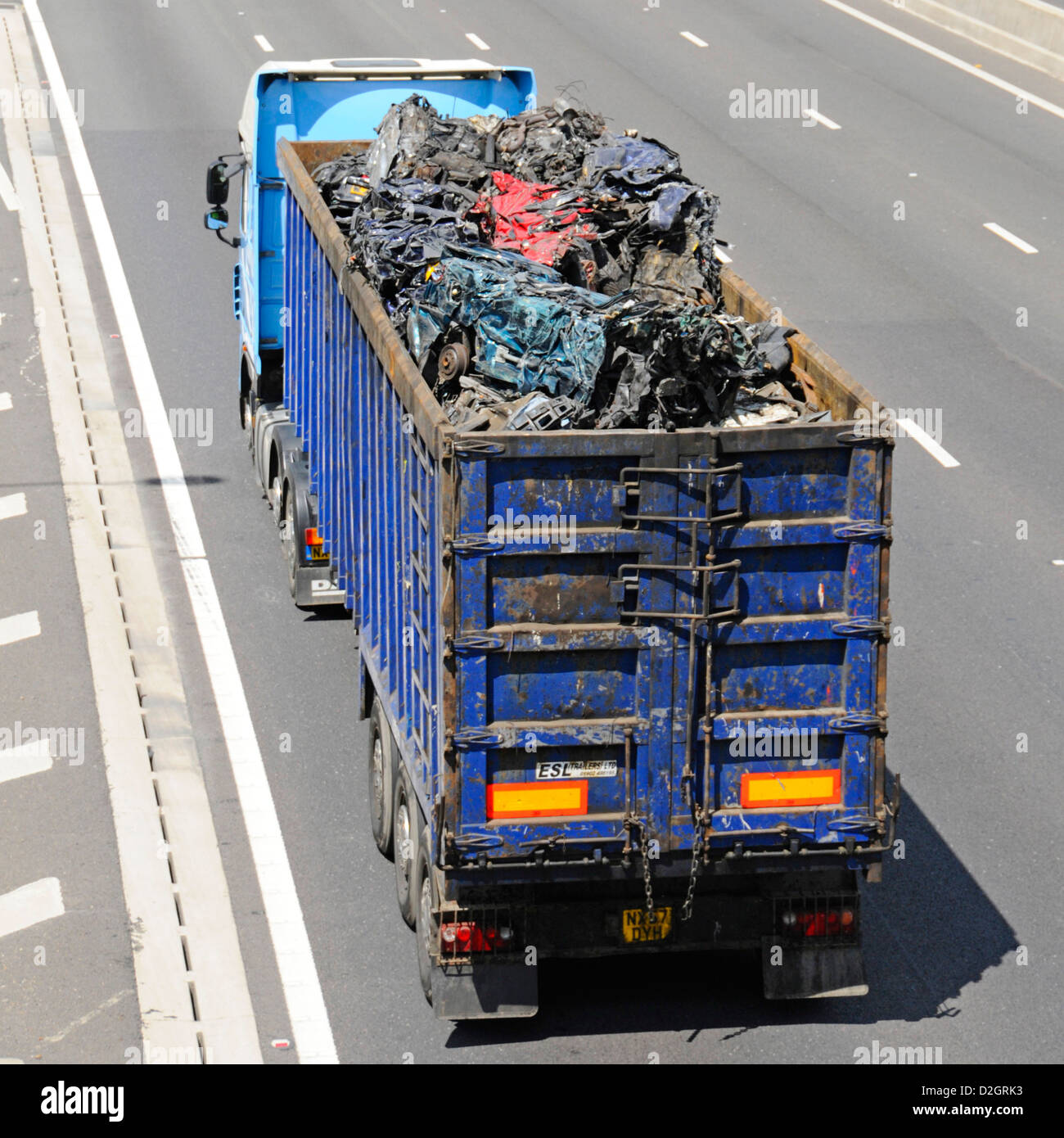 Looking down overhead view at hgv lorry truck load of scrap metal  crushed motor cars in open articulated trailer for recycling driving on UK motorway Stock Photo