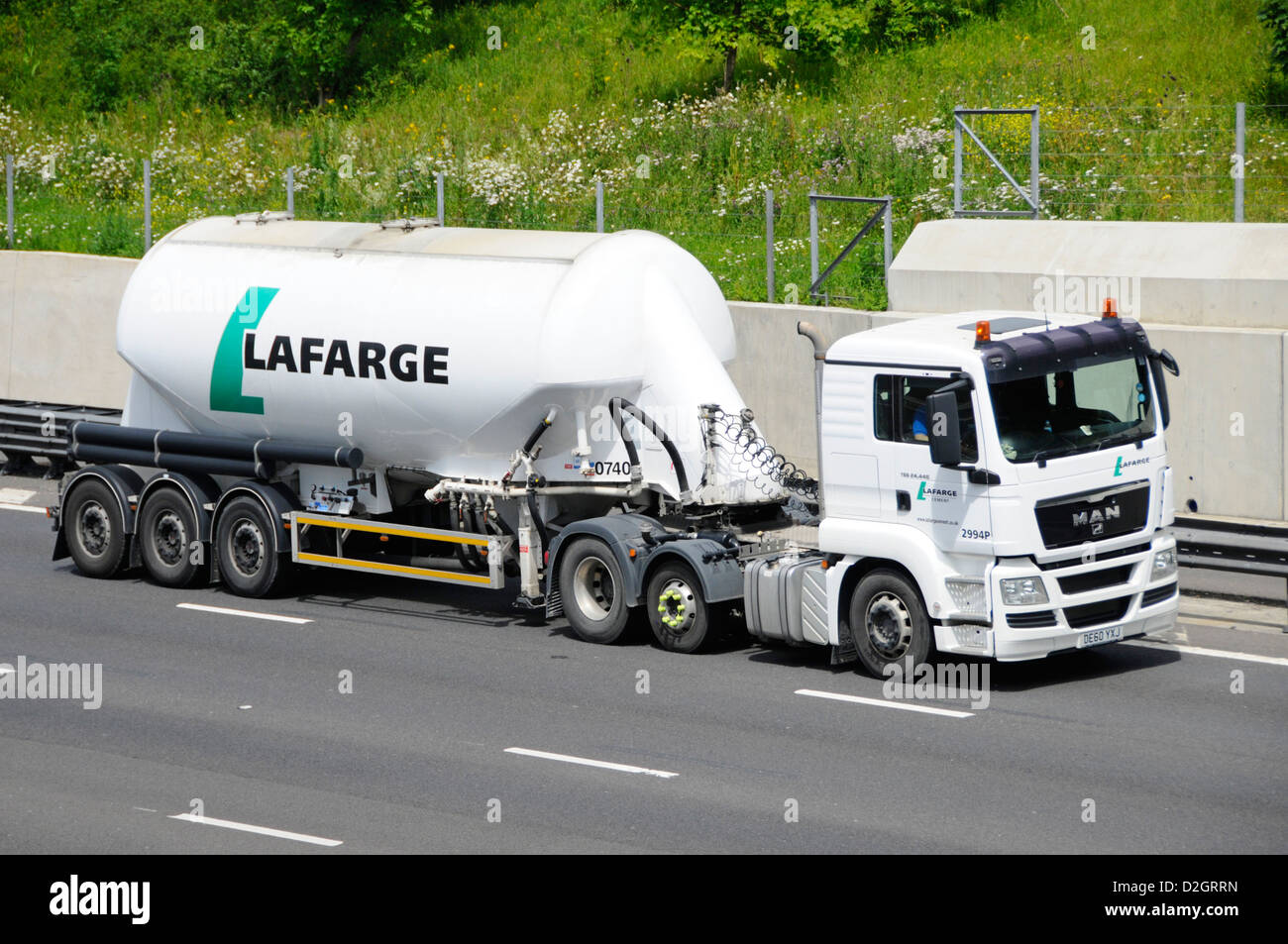 Side view LaFarge bulk cement powder carrier in articulated tanker trailer towed by white hgv lorry truck driving along M25 motorway Essex England UK Stock Photo