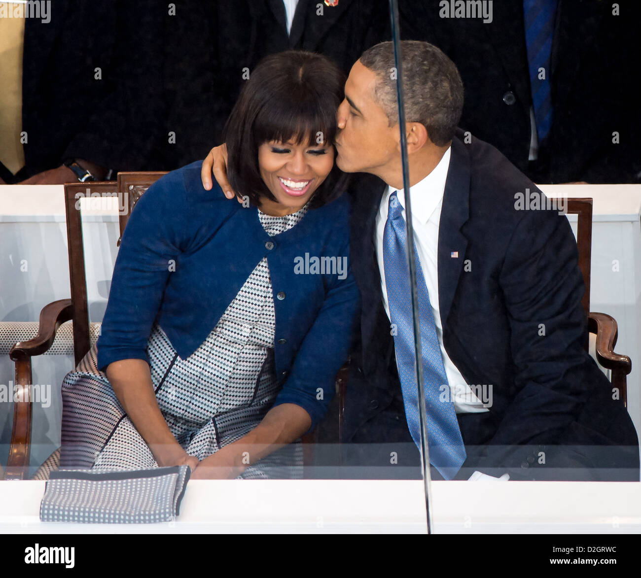 US President Barack Obama kisses first lady Michelle Obama while seated in the presidential reviewing stand during the inaugural parade January 21, 2013 in Washington, DC. Obama was sworn-in as the nation's 44th President earlier in the day. Stock Photo