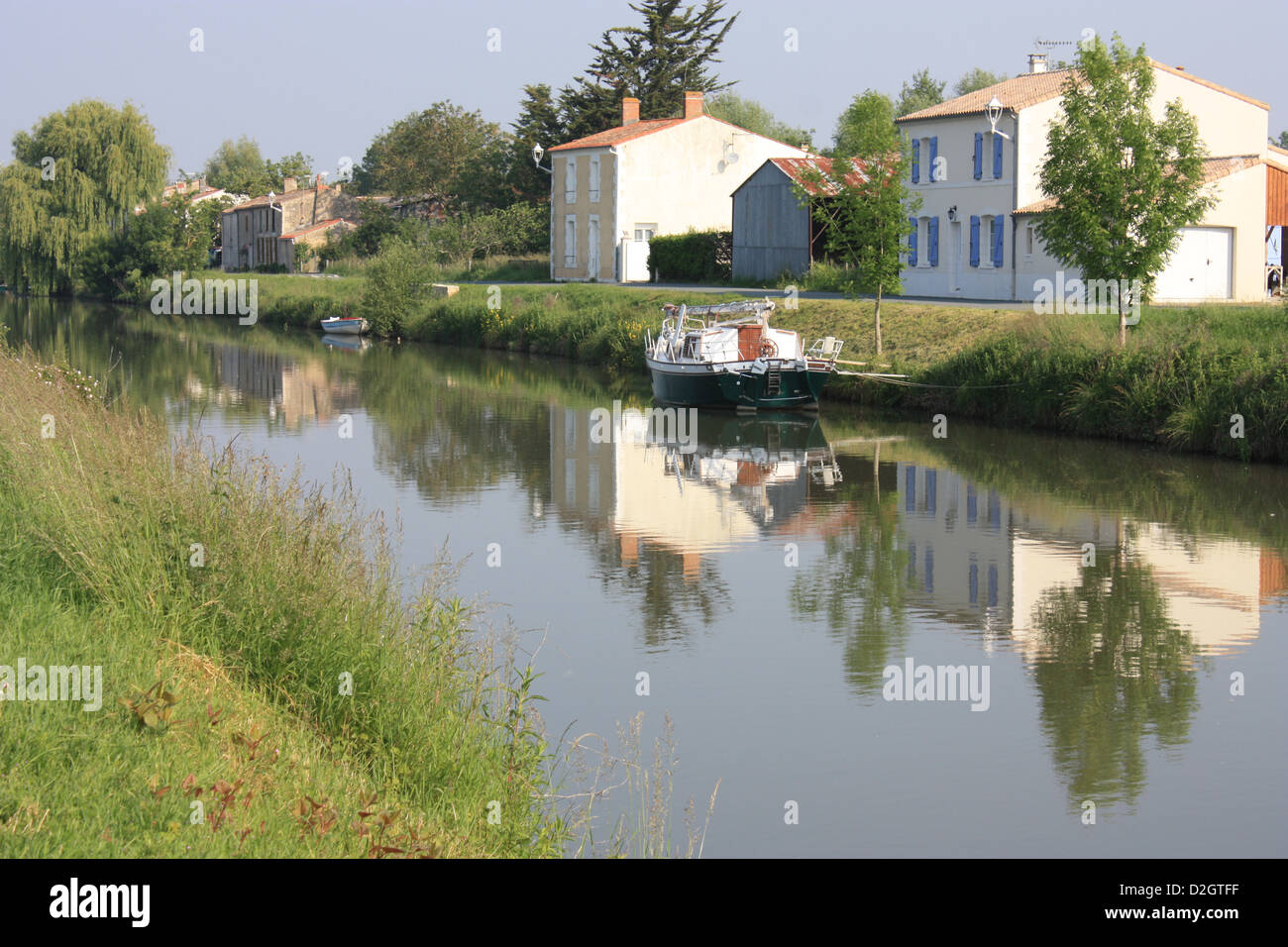 Typical houses of the Marais Poitevin are reflected in the Sevre-Niortaise river at Damvix in the Vendee Stock Photo