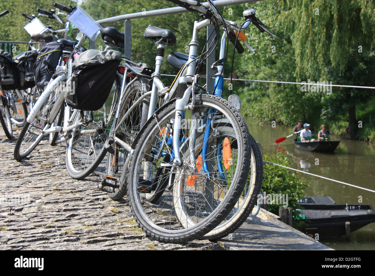 Bicycles propped against a railing beside a canal at Arcais in the Marais Poitevin, Poitou-Charentes, France Stock Photo
