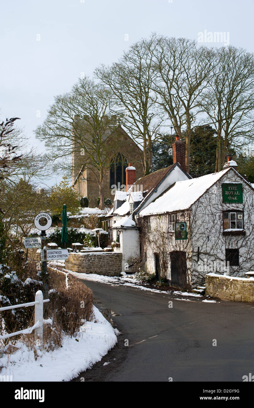 Royal Oak pub and church in winter snow Cardington Shropshire UK Stock Photo