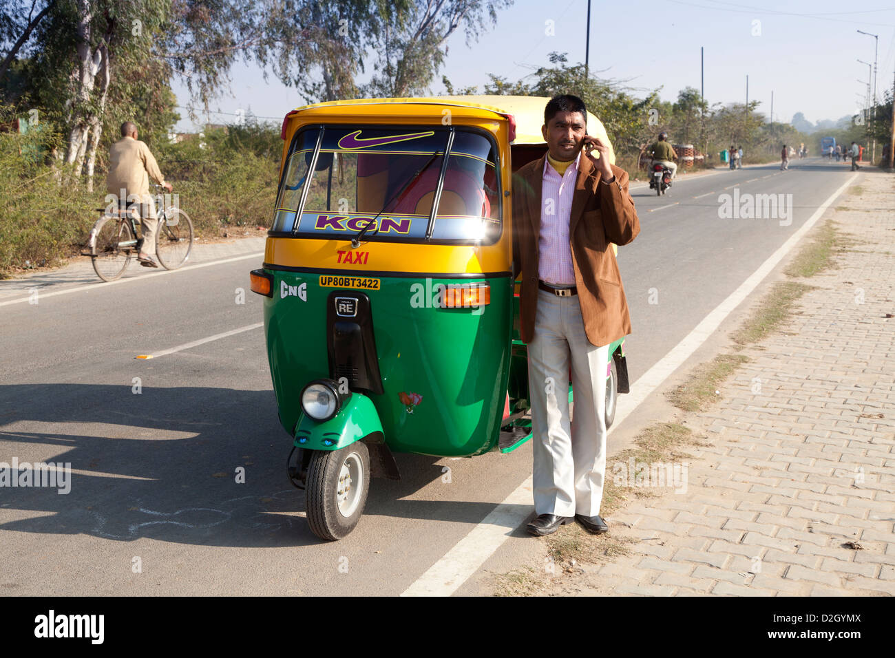 successful rickshaw driver with new rickshaw using mobile phone. Model