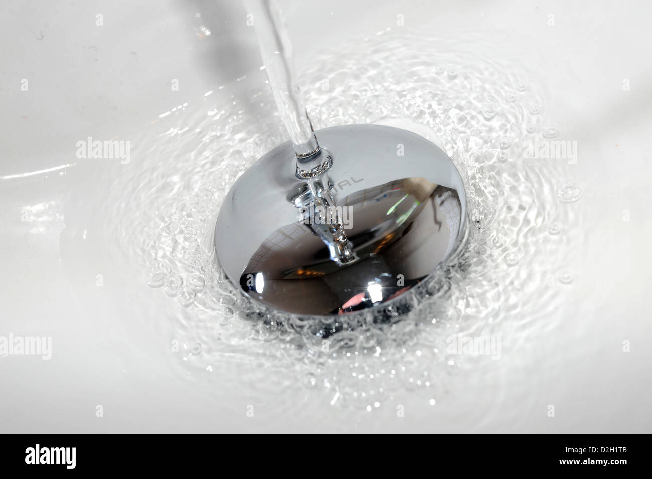 Water running down a bathroom sink plug hole Stock Photo