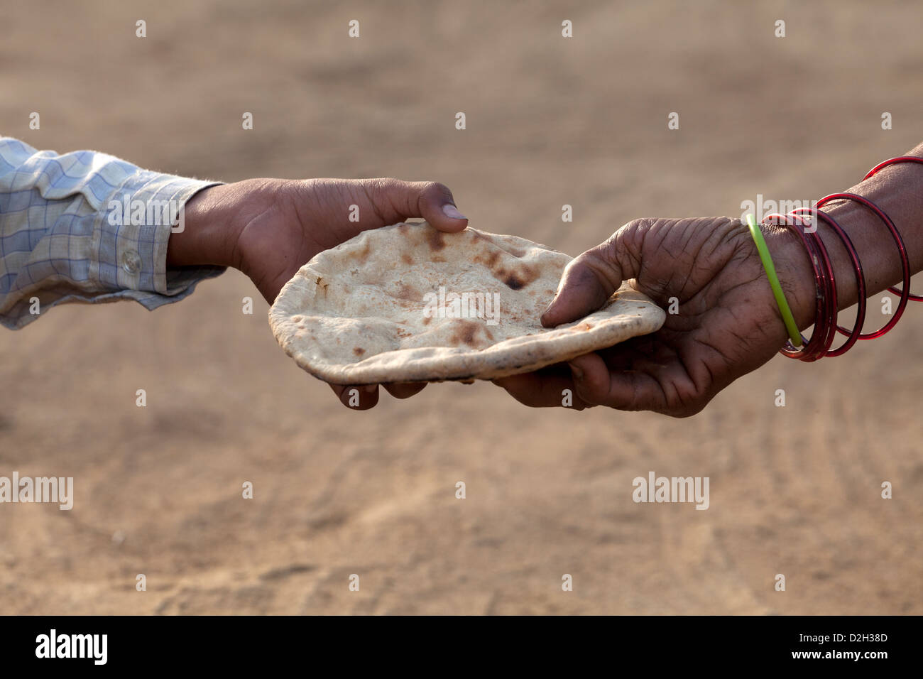India, Uttar Pradesh, Agra, young boy's hand being given Roti (Chapati) by mother's hand Stock Photo
