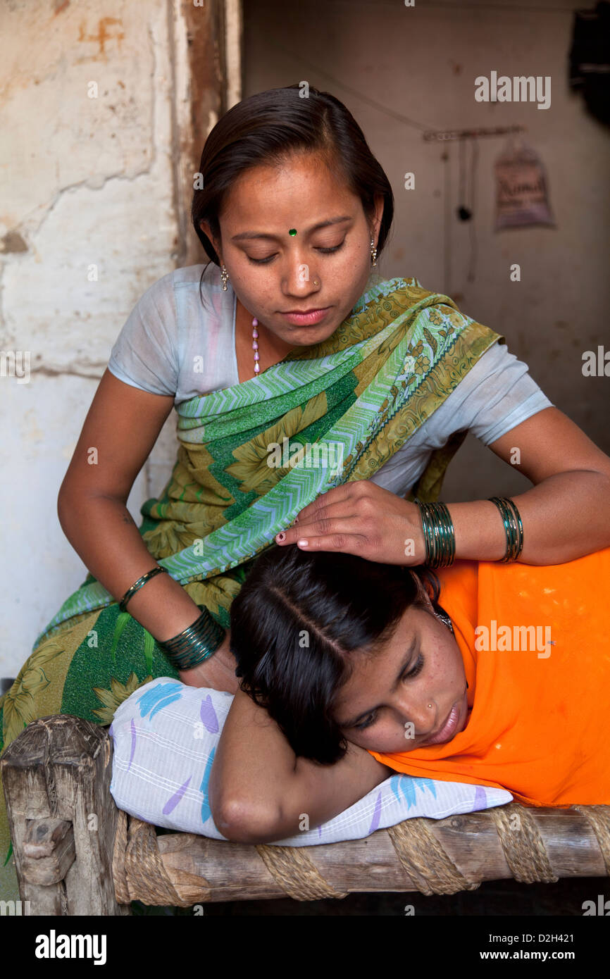 India, uttar Pradesh, Agra Older adult sister comforting younger teenage sister who has mosquito bites on face Stock Photo