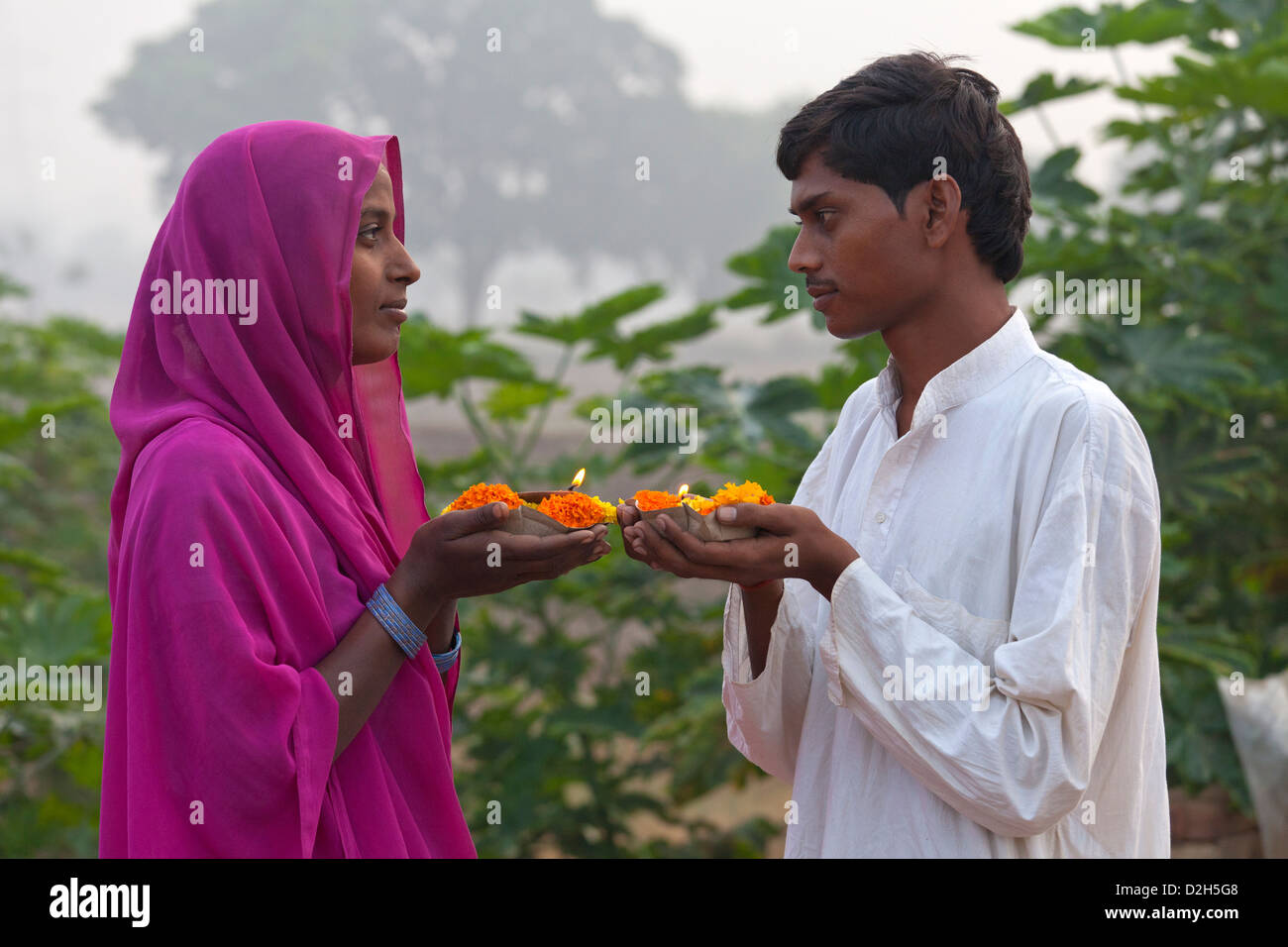 india, Uttar Pradesh, young hindu man and woman holding prayer lamp and marigolds Stock Photo