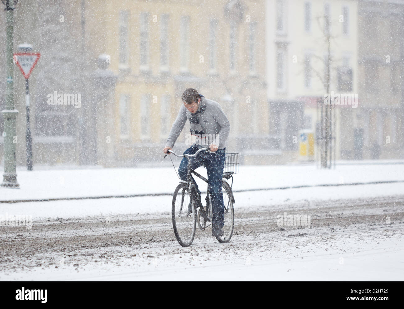A student cycles through central Oxford during heavy snow Stock Photo