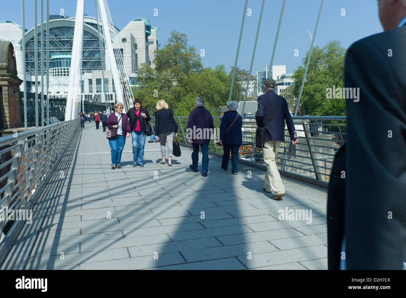London, Southbank, Riverside, Embankment, Hungerford Bridge commuters tourists walking across bridge on a sunny day Stock Photo