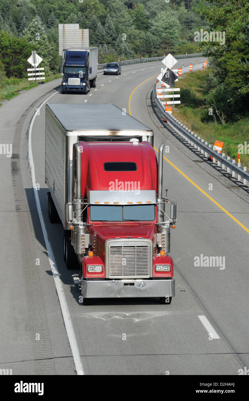 Truck traffic moving on an American interstate highway, commercial freight hauling westbound in afternoon sunlight. Stock Photo