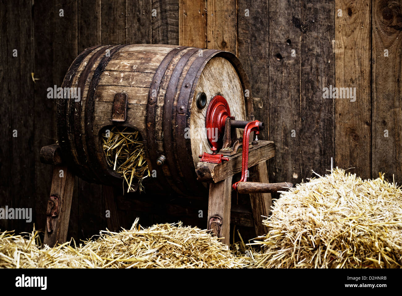 Vintage barreltype butter churn filled with straw, wooden background