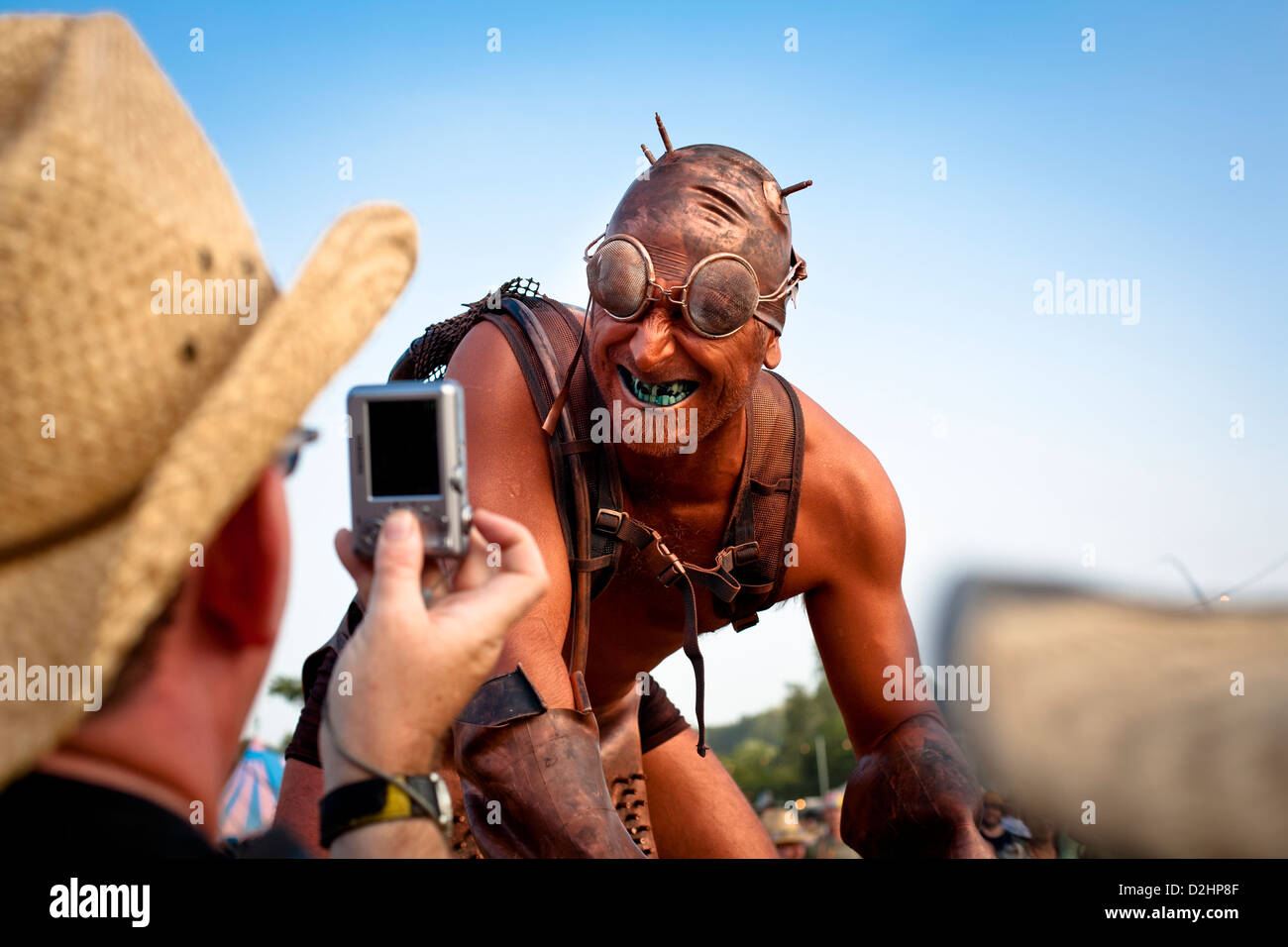 A man takes a photo of a colourful 'walkabout' performer at Glastonbury Festival in 2010. These performers roam the site, entert Stock Photo