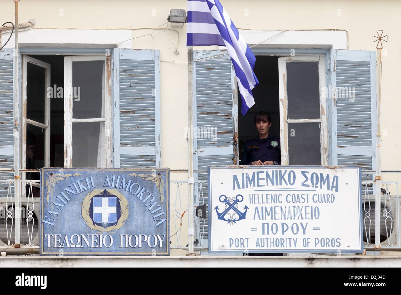 A young Coast Guard officer looks out of the window of the dilapidated coastguard office on the island of Poros, Greece Stock Photo