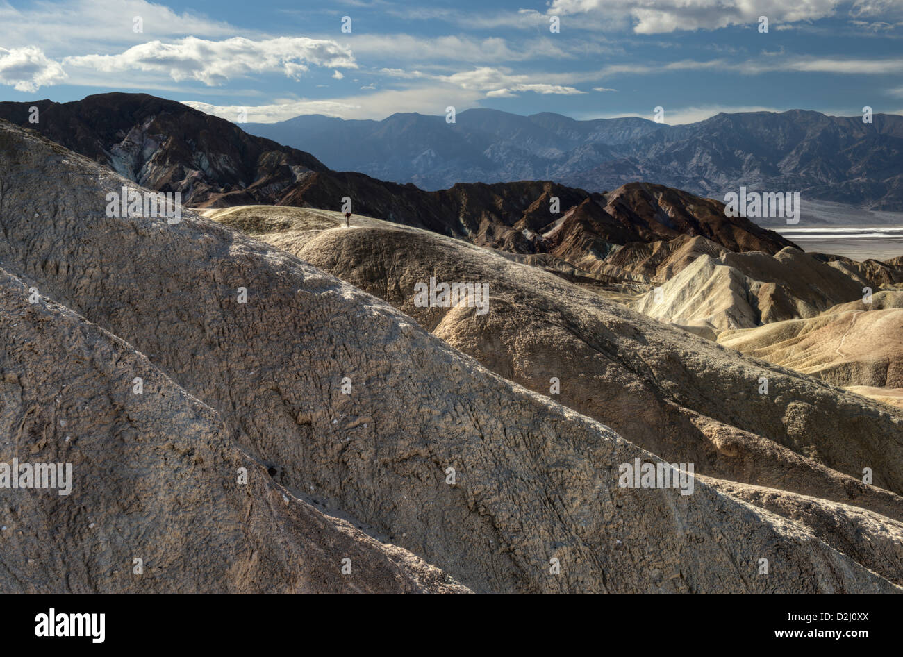 A hiker ascends the ridges of mudstone at Zabriskie Point in Death Valley National Park, California Stock Photo