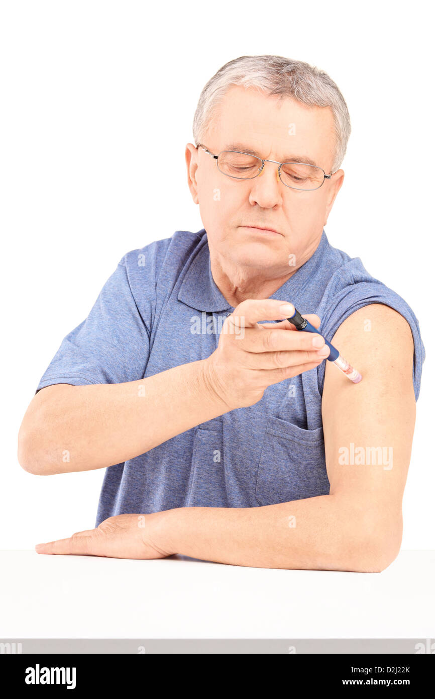 Mature man sitting and injecting insulin in his arm isolated on white background Stock Photo