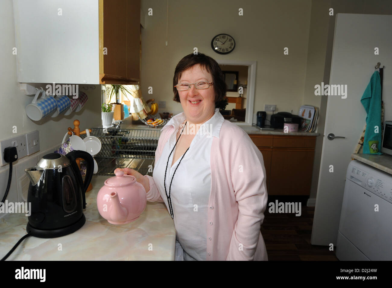 A young disabled  women makes tea in the kitchen, she lives independently with help from her carer. Stock Photo